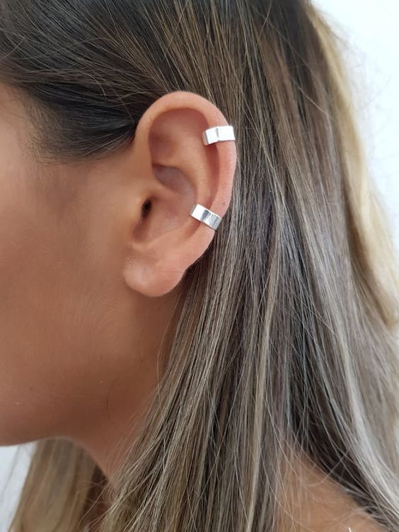 A woman wearing a silver ear cuff, adding a touch of elegance to her look.