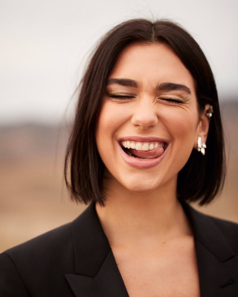 Woman in black suit laughing.