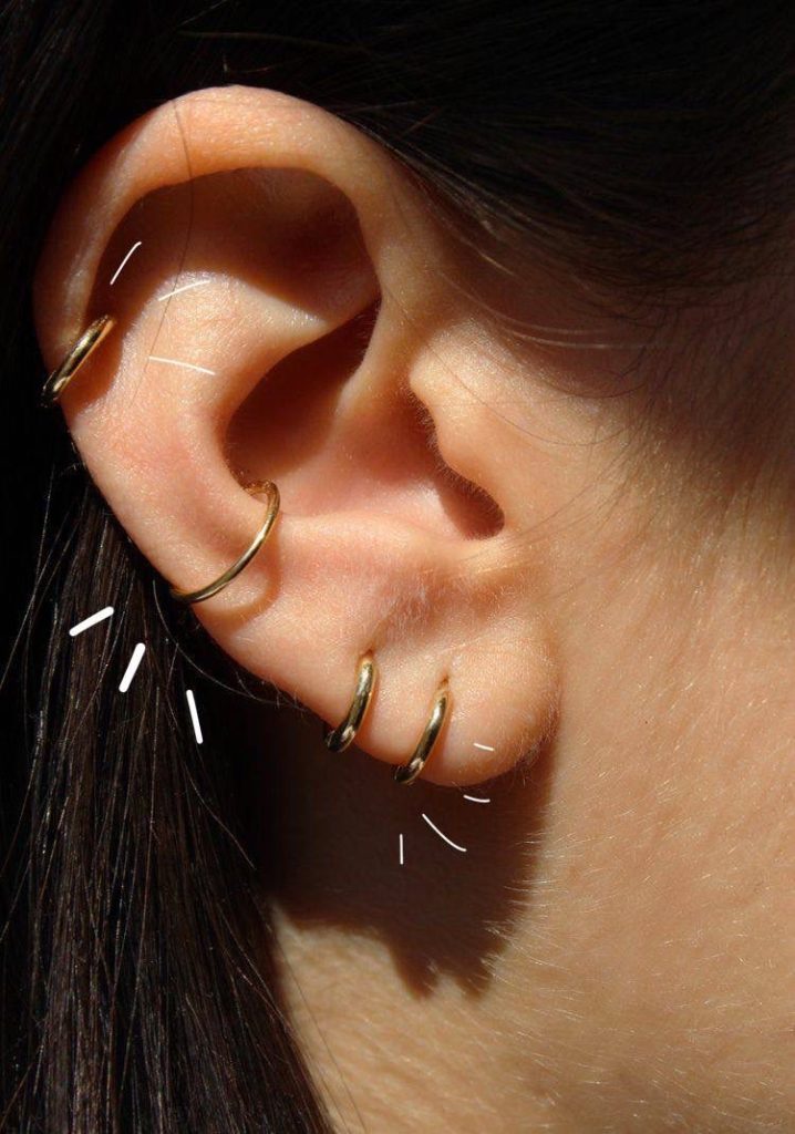 A woman with two ear piercings, wearing earrings with adorable miniature charms.